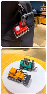 Close-up of colorful alloy excavator and forklift keychains hanging on a backpack