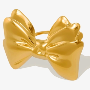 Macro detail of high-polished gold bow ring showing the minimalist metallic textures