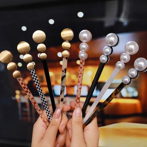 Macro view of acetate hair pins with golden disc and pearl details in various patterns