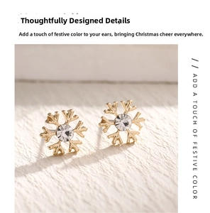 Close-up of golden snowflake stud earrings with a sparkling white rhinestone center
