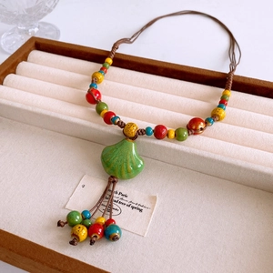 Close-up of bohemian ceramic bead necklace with colorful stones and leaf pendant