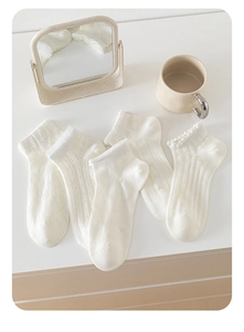 Detail shot of five white ballet-style cotton socks showing hollow mesh and lace textures