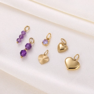 Detailed macro view of gold heart pendants and purple crystal charms on soft fabric