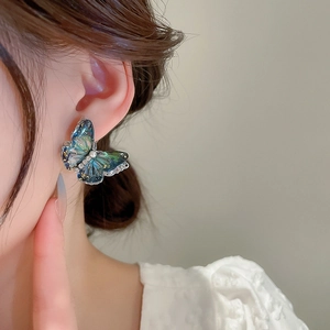 Détail de la boucle d'oreille papillon avec dégradé bleu-vert et perle centrale