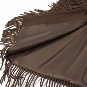 Détail d'un manteau en laine marron avec doublure en satin et finitions à franges