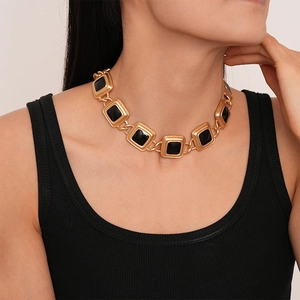 Detail of vintage square gold necklace with black enamel inlay on model neck