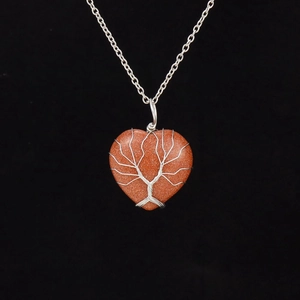 Detail of handmade silver wire tree of life wrapped around a heart goldstone pendant