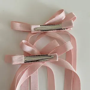 Vue détaillée des barrettes à nœuds en ruban de soie rose avec de longs rubans fluides