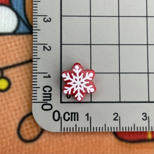 Macro view of a 1.2cm red resin snowflake button with white details on a grid ruler