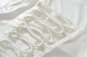 Dettaglio dell'abito in raso bianco con elegante lacci incrociati sulla schiena e trama