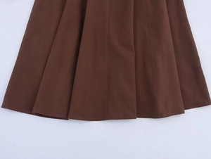 Gros plan détaillé de l'ourlet d'une robe marron foncé montrant les coutures et la texture