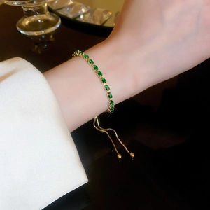 Detail of adjustable gold bracelet featuring green teardrop cubic zirconia stones