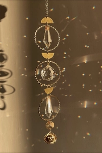 Golden suncatcher with crystal prisms and sun face pendant creating rainbow light spots