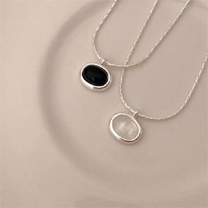 Detail of 925 sterling silver necklaces with oval black onyx and white gemstone pendants