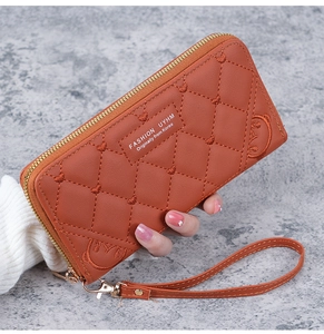 Caramel long wallet with heart embroidery and quilted pattern held by hand