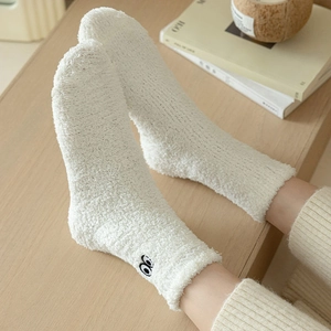 Close-up of white coral fleece sock featuring cute embroidered eyes on the side