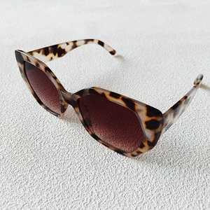 Detailed close-up of retro tortoiseshell frame sunglasses with brown gradient lenses