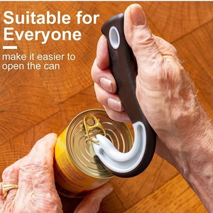 Ergonomic black and white jar opener hook lifting a can tab on a wooden background