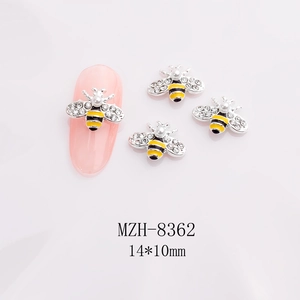 Macro shot of 3D bee nail art charm with yellow enamel and pearl on pink gradient background