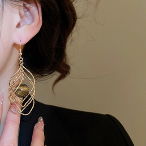 Close-up of model wearing twisted gold diamond-shaped tiger eye stone drop earrings