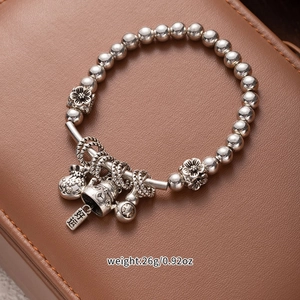 Detail of silver beaded tassel bracelet with lucky cat and fortune bag charms on leather