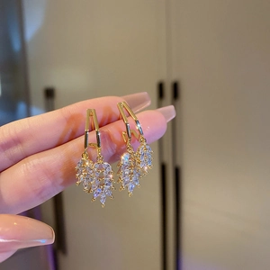 Detailed close-up of golden geometric earrings with sparkling zircon leaf-shaped tassels