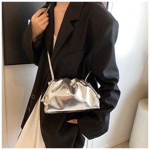 Close-up of metallic silver cloud clutch bag with pleated texture and thin shoulder strap