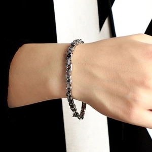 Polished silver stainless steel Byzantine chain bracelet worn by a male model on wrist