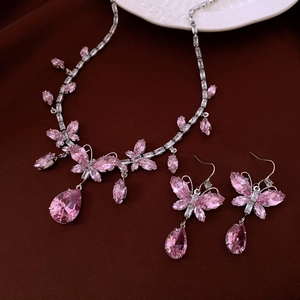 Halskette und Ohrringe Set mit rosa Kristall-Schmetterlingen auf weißem Teller