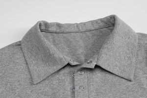 Detail of grey knitted polo shirt with silver metal snap buttons and lapel collar texture