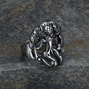 Macro shot of silver Tree of Life steel ring with vintage texture on a dark rock background