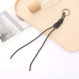 Deep grey rhinestone braided keychain with metal ring on a minimalist tray