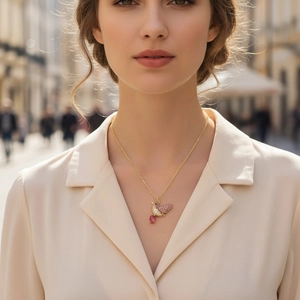 Close-up of gold bird pendant necklace with pink and clear zircons worn by a model
