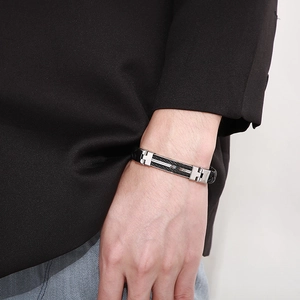 Detail of men's black braided leather bracelet with silver steel clasp on a suit cuff