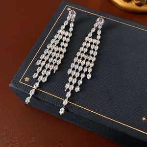 Macro shot of silver tassel earrings with zircon inlay on a blue velvet jewelry box