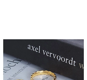 Detail of two wavy gold titanium steel rings with a polished geometric scalloped design