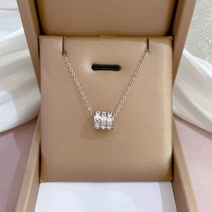 Detailed shot of a silver titanium necklace with a stone-encrusted cylinder pendant in a box