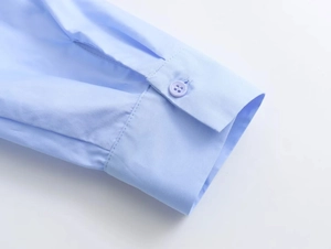 Close-up of light blue poplin shirt cuff with matching resin button and fine stitching