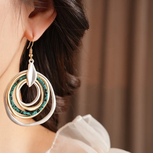 Close-up of bohemian layered irregular round earrings with gold and green accents