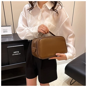 Detailed close-up of brown leather toiletry bag with double zipper and sturdy handle