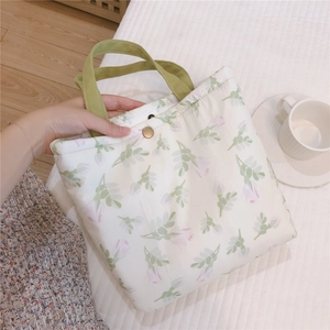 Détail du petit sac en coton aux motifs floraux roses avec des poignées vertes