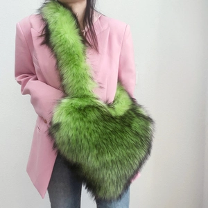 Green faux fur crossbody bag shown on model with pink suit for size demonstration