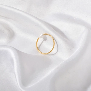 Anello minimalista in oro 18 carati con perla bianca su elegante sfondo di seta bianca