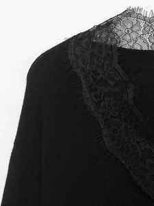 Detailed close-up of delicate black eyelash lace floral pattern on a V-neck knit top