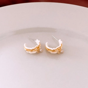 Detailed close-up of C-shaped 18k gold plated enamel earrings with zircon crystals