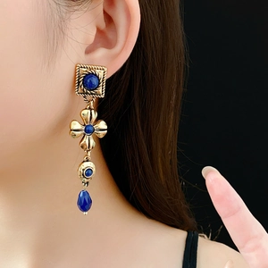 Close-up of vintage gold floral earrings with blue gems worn by a model