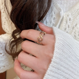 Detailed close-up of a gold hollow smiley face ring worn on the finger in a lifestyle setting
