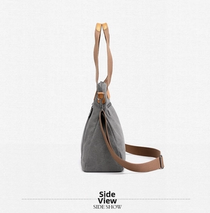 Side view of gray canvas tote bag featuring brown handles and side zipper pocket detail