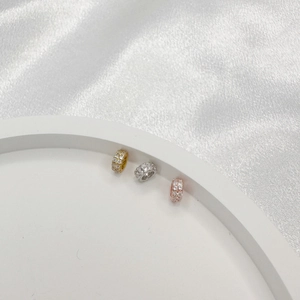 Macro shot of silver, gold and rose gold spacer beads with inlaid clear zircons