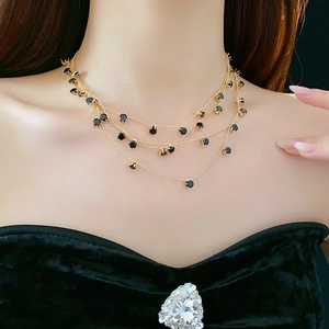 Détail d'un collier doré multicouche avec pierres noires porté par un mannequin